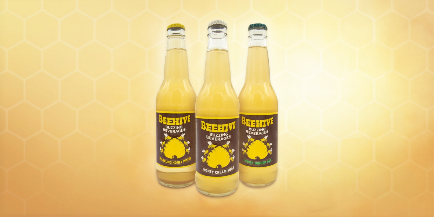 Collection of Avery’s Honey-Infused Sodas in glass bottles on gradient yellow background
