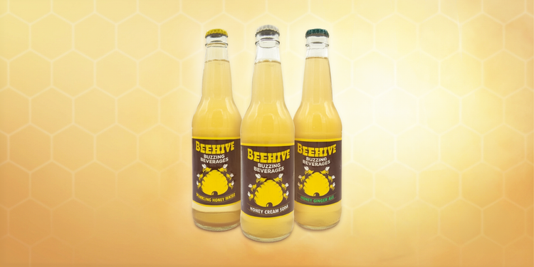 Collection of Avery’s Honey-Infused Sodas in glass bottles on gradient yellow background