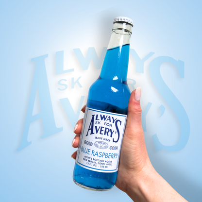 Hand holding a bottle of Avery’s Blue Raspberry Soda in glass bottle on blue gradient background
