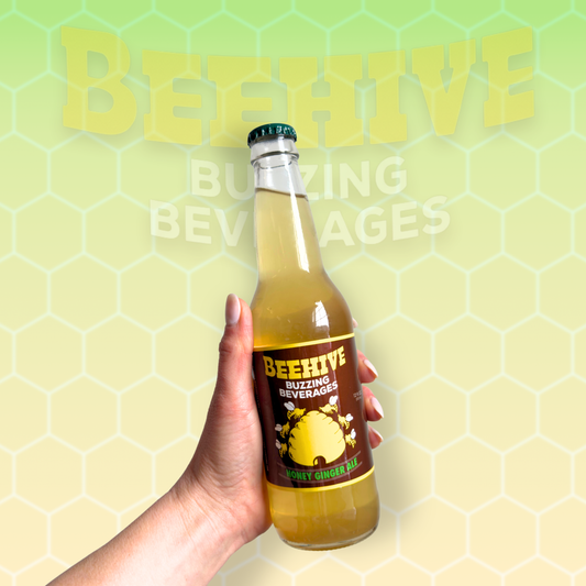 Hand holding a bottle of Avery’s Honey Infused Ginger Ale in glass bottle on yellow and green gradient background