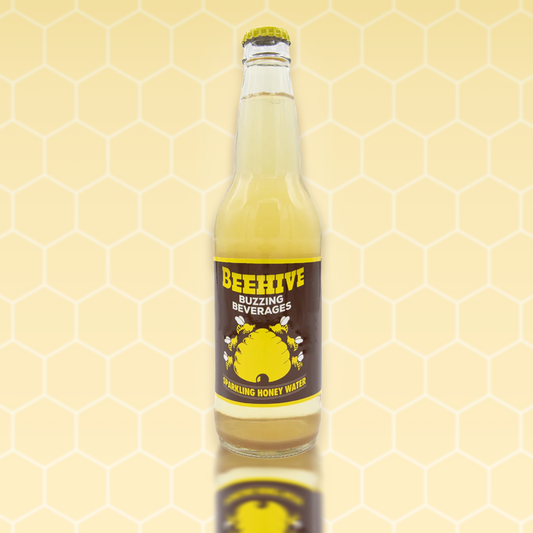 Avery’s Honey Infused Sparkling Honey Water in glass bottle on yellow honeycomb background