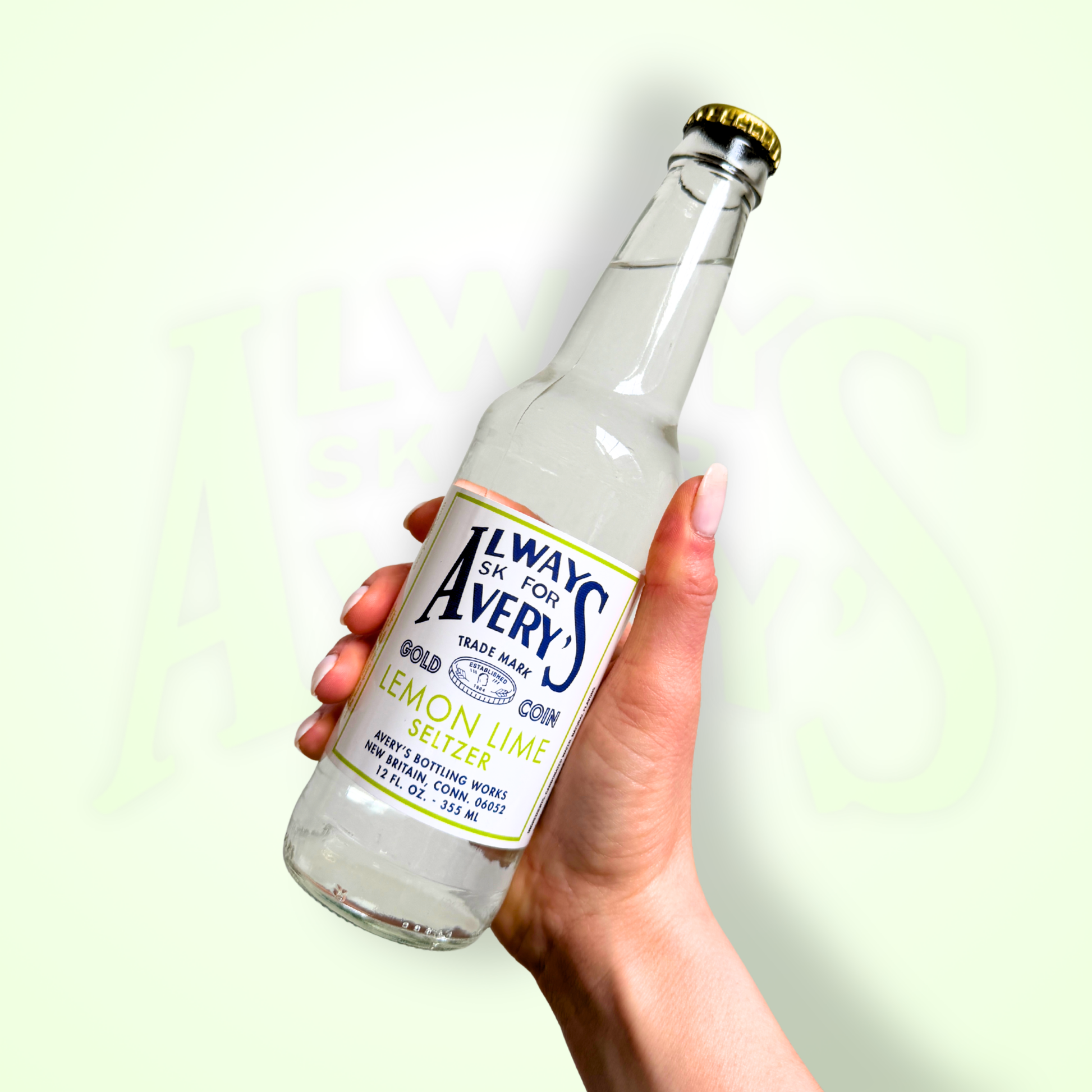 Hand holding bottle of Avery’s Lemon Lime Seltzer in glass bottle on green gradient background