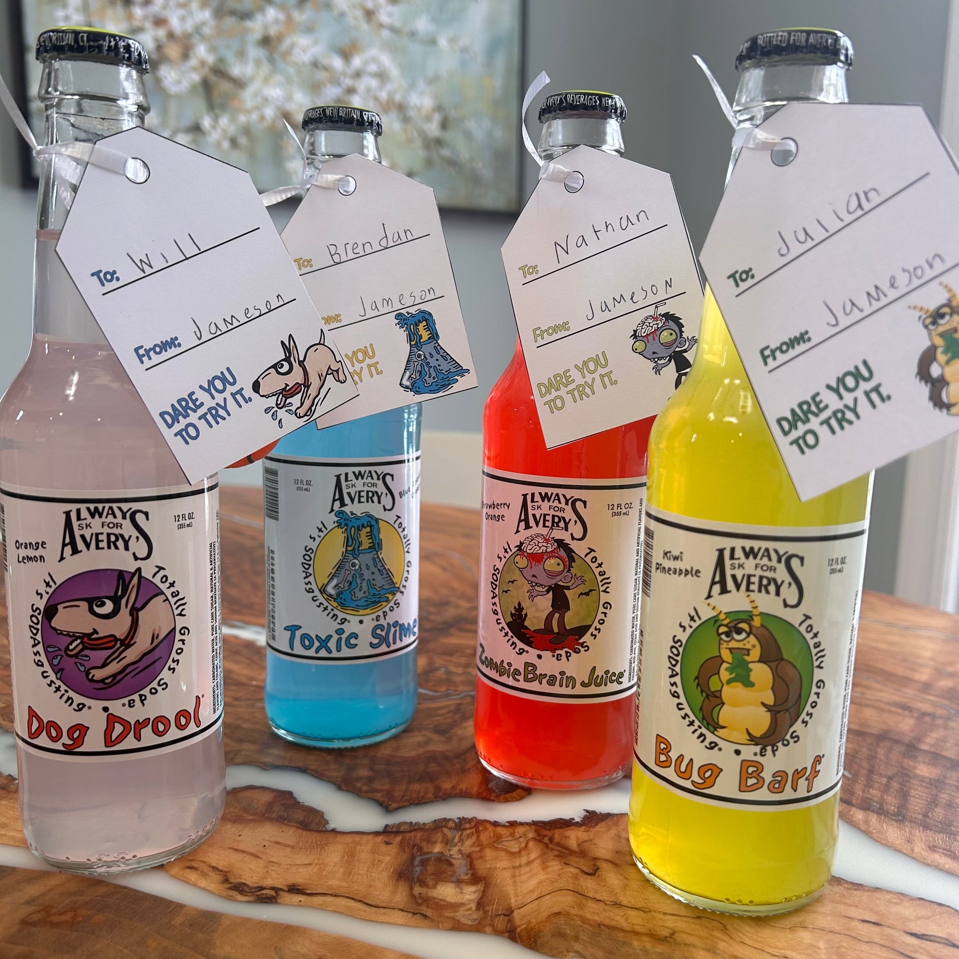 Avery's Totally Gross gifting tags hanging from colorful glass bottles with to and from names handwritten on the tags